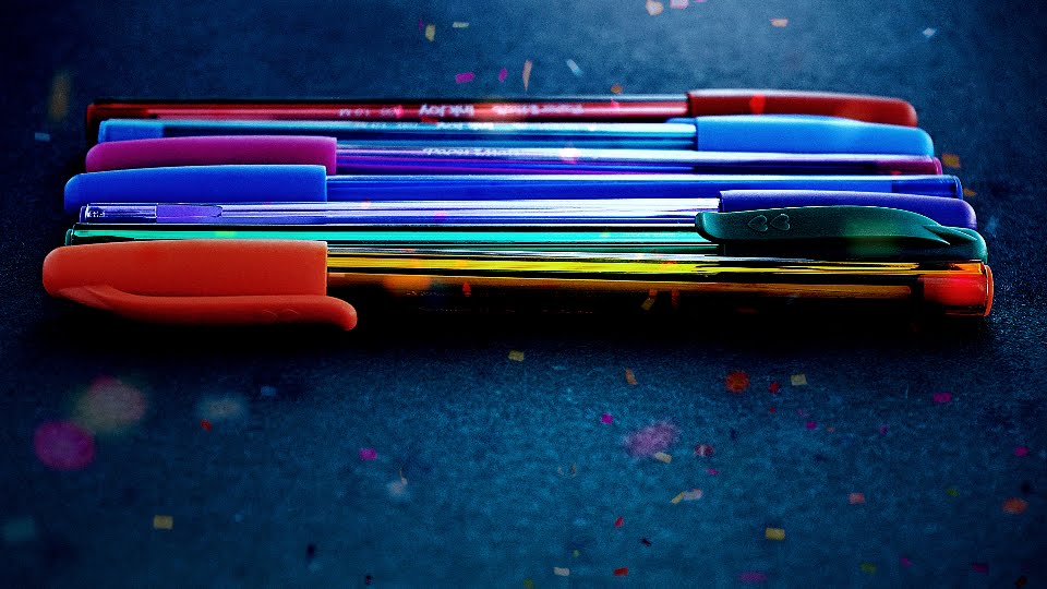 a series of six multicoloured pens lined up on a table