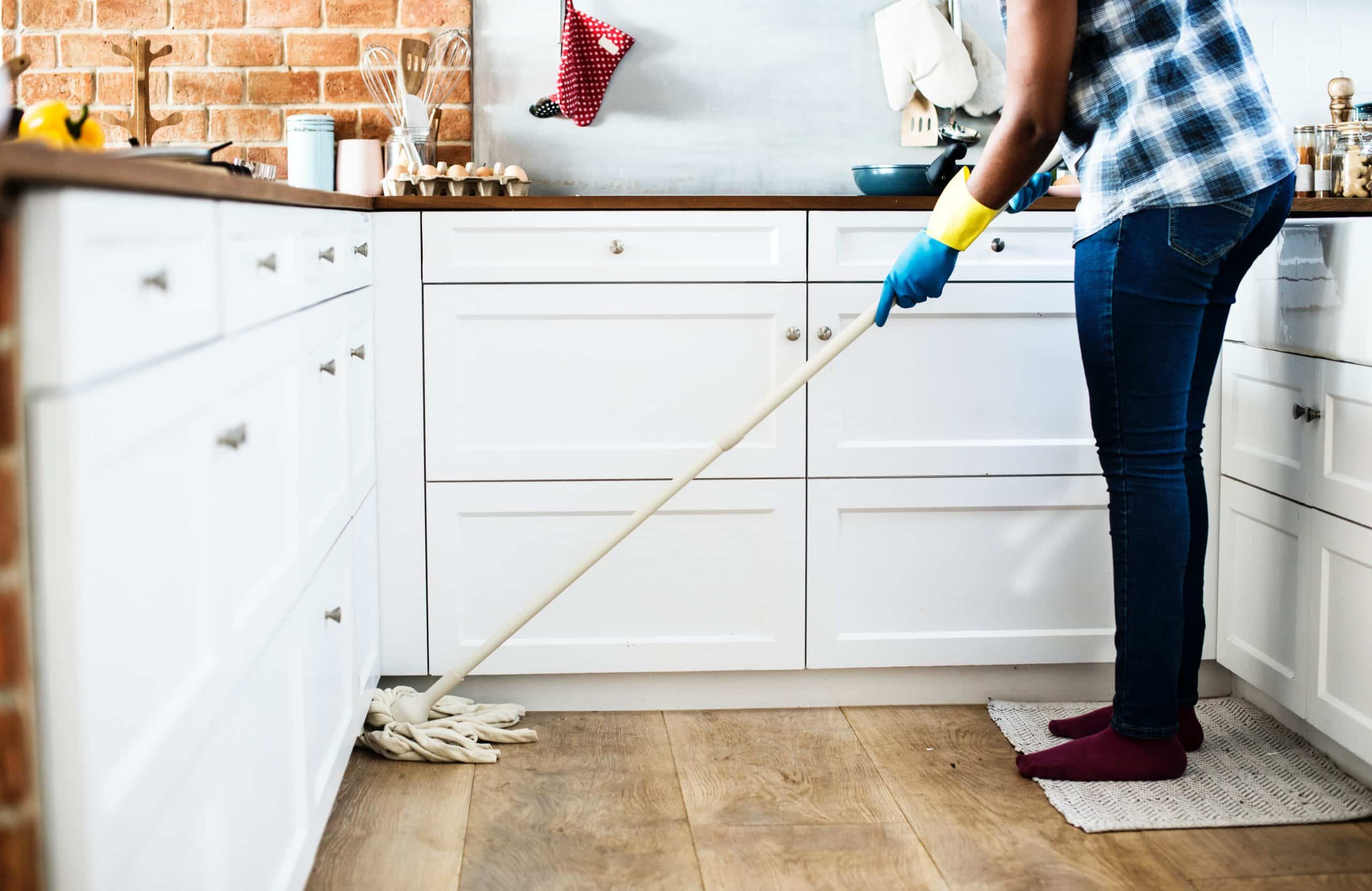 woman cleaning kitchen floor representing employee of cleaning company