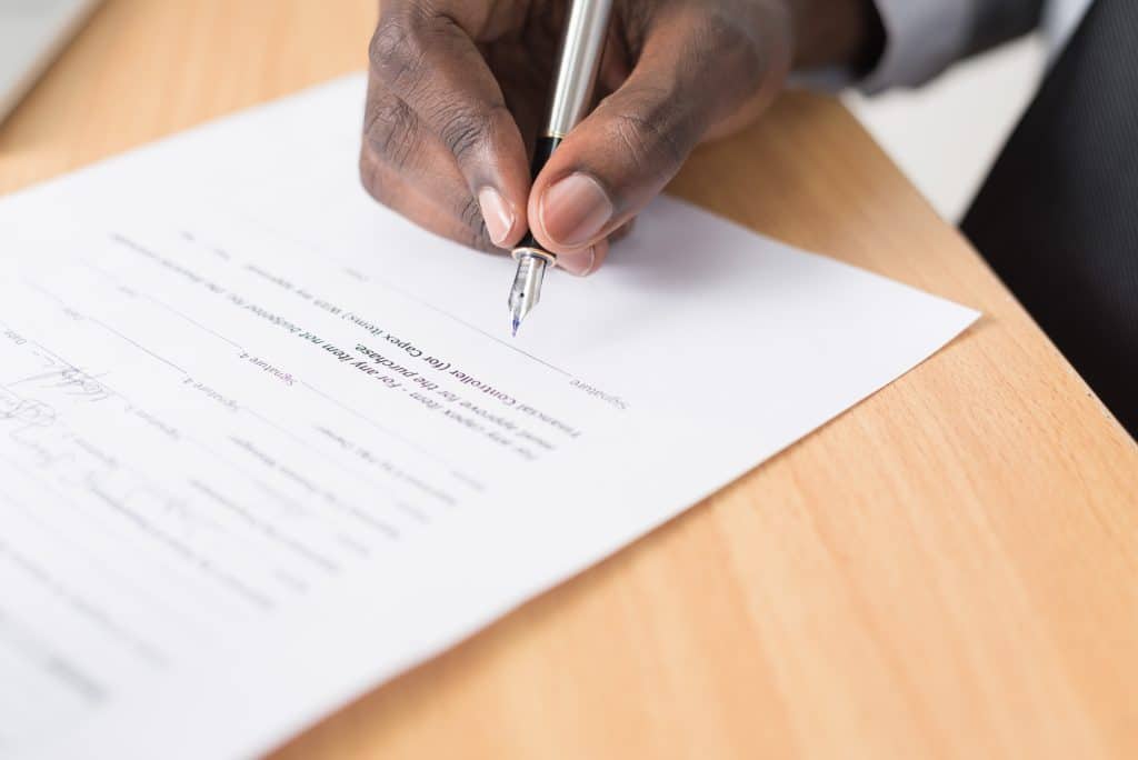 a man's hand signing a contract