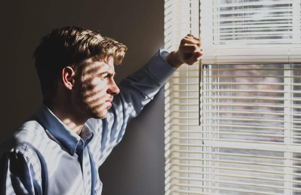 A man looking out a window representing an employee facing mistreatment at work