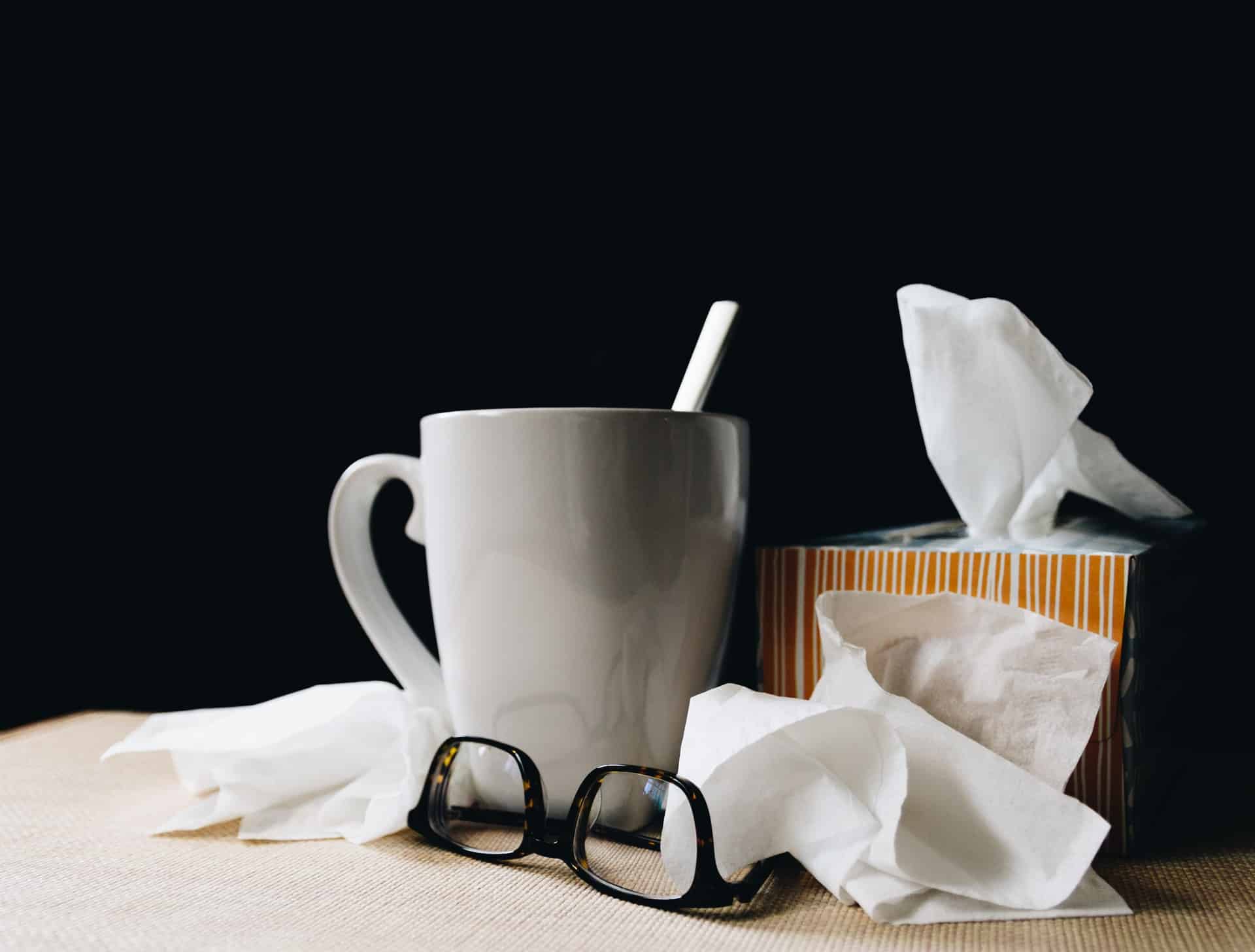 Tea and tissues on a table representing staying home from work when sick