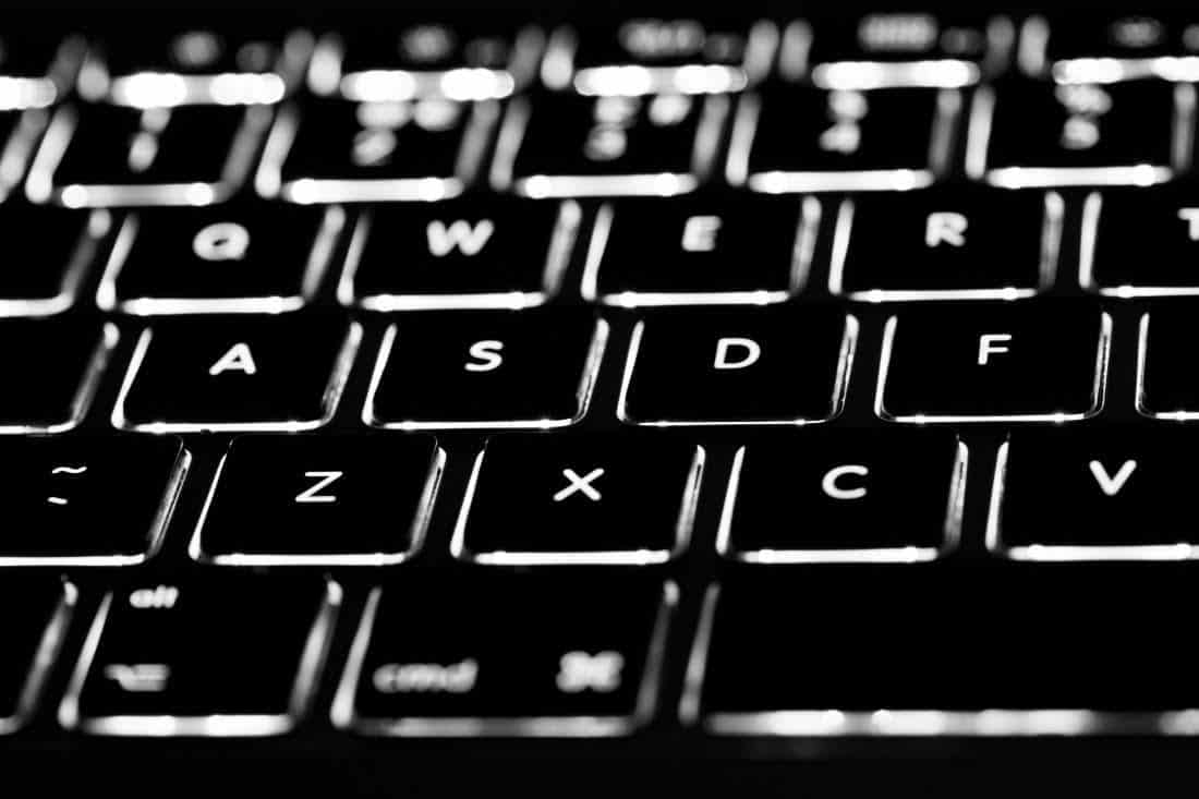 close up of black computer keyboard with keys backlit by white light