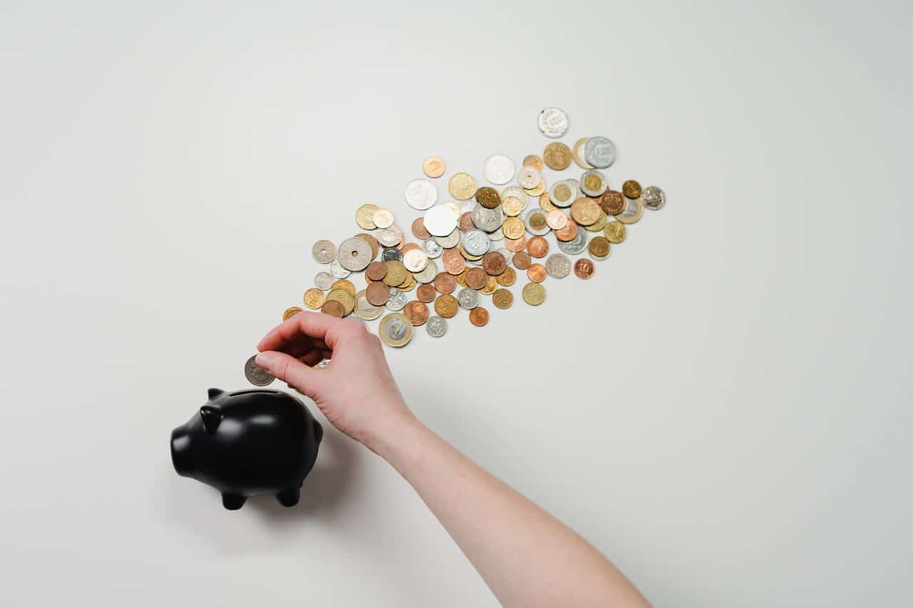 A person putting coins into a piggy bank representing commission earned after termination