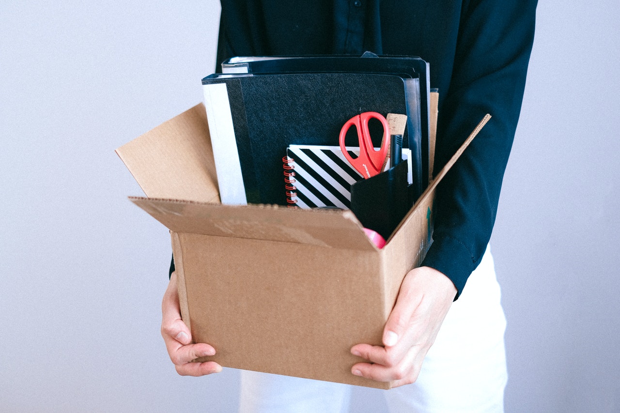 A woman carrying a box of office equipment representing an employee terminated for cause