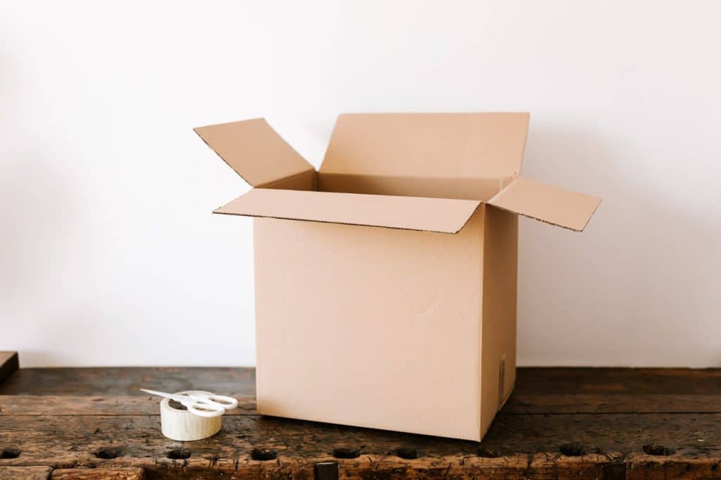 A cardboard box, scissors and tap on a wooden desk representing an employee terminated after 5 months