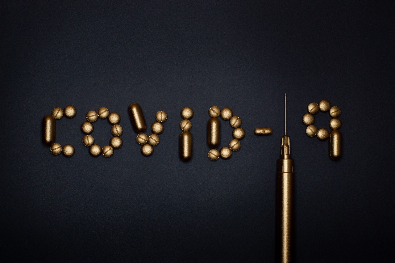 The phrase COVID-19 spelled out in pills with a syringe, representing the question of whether an employer can force an employee to get vaccinated against COVID-19