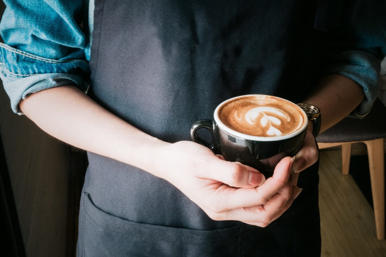 A barista serving a coffee representing Canadian coffee shop managers who brought a class action for overtime pay