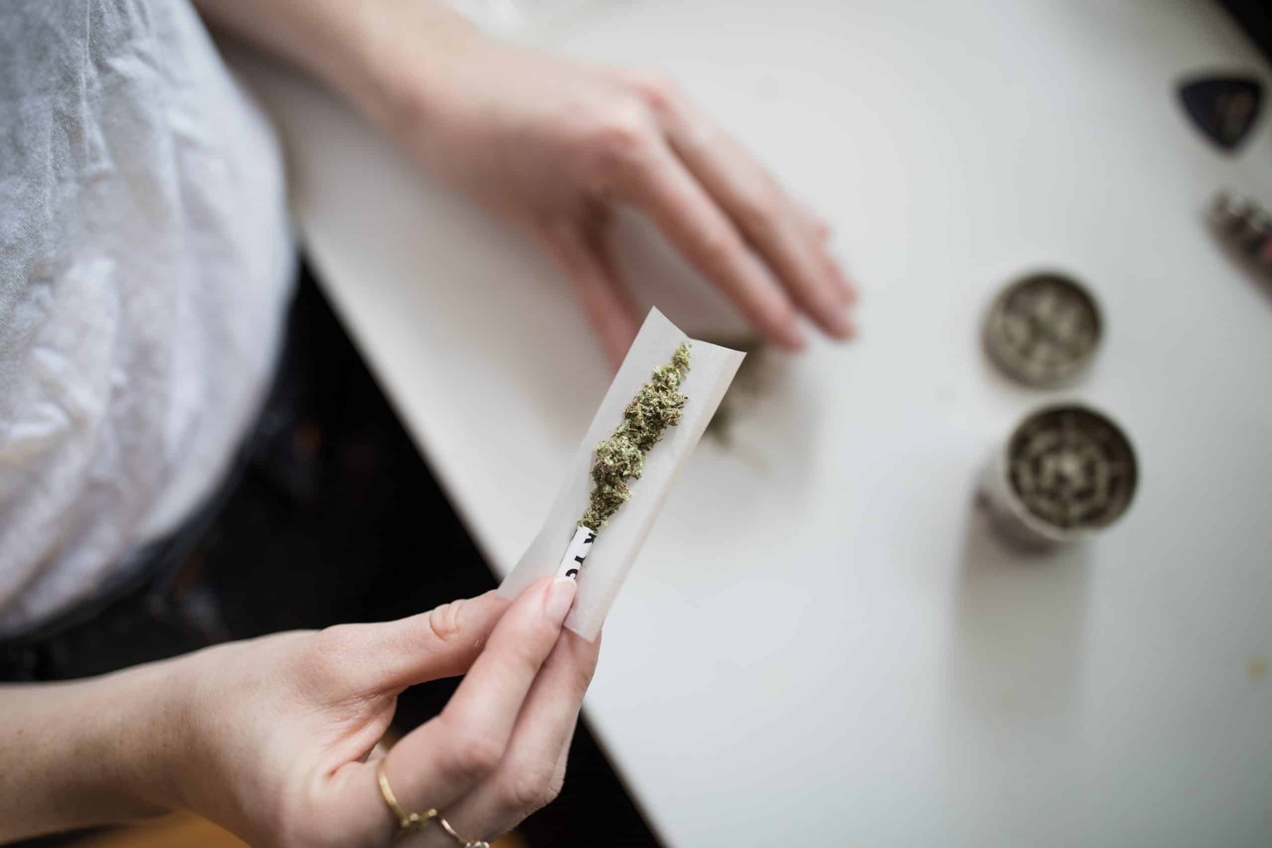 A person rolling a joint, representing drug use at work