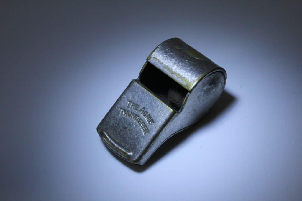 vintage metal whistle against a grey background