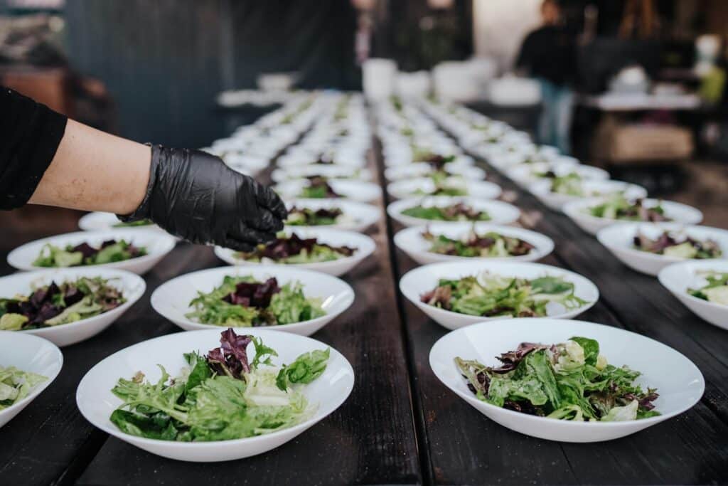 a person finishing bowls of salad for a catering event