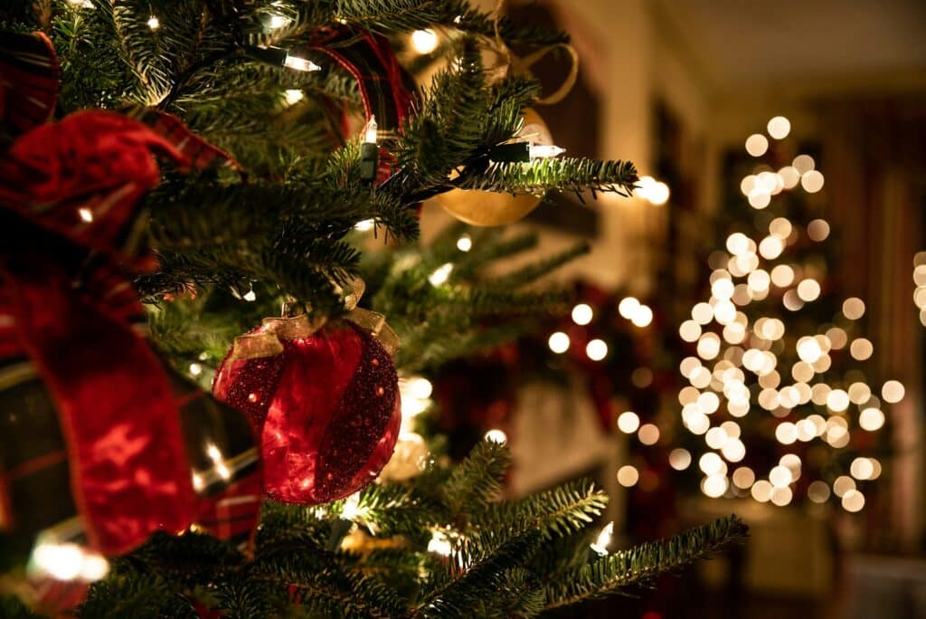 Close-up of a decorated Christmas tree with a red ornament and ribbon, representing holiday employment law risks and office party liability for Ontario businesses.
