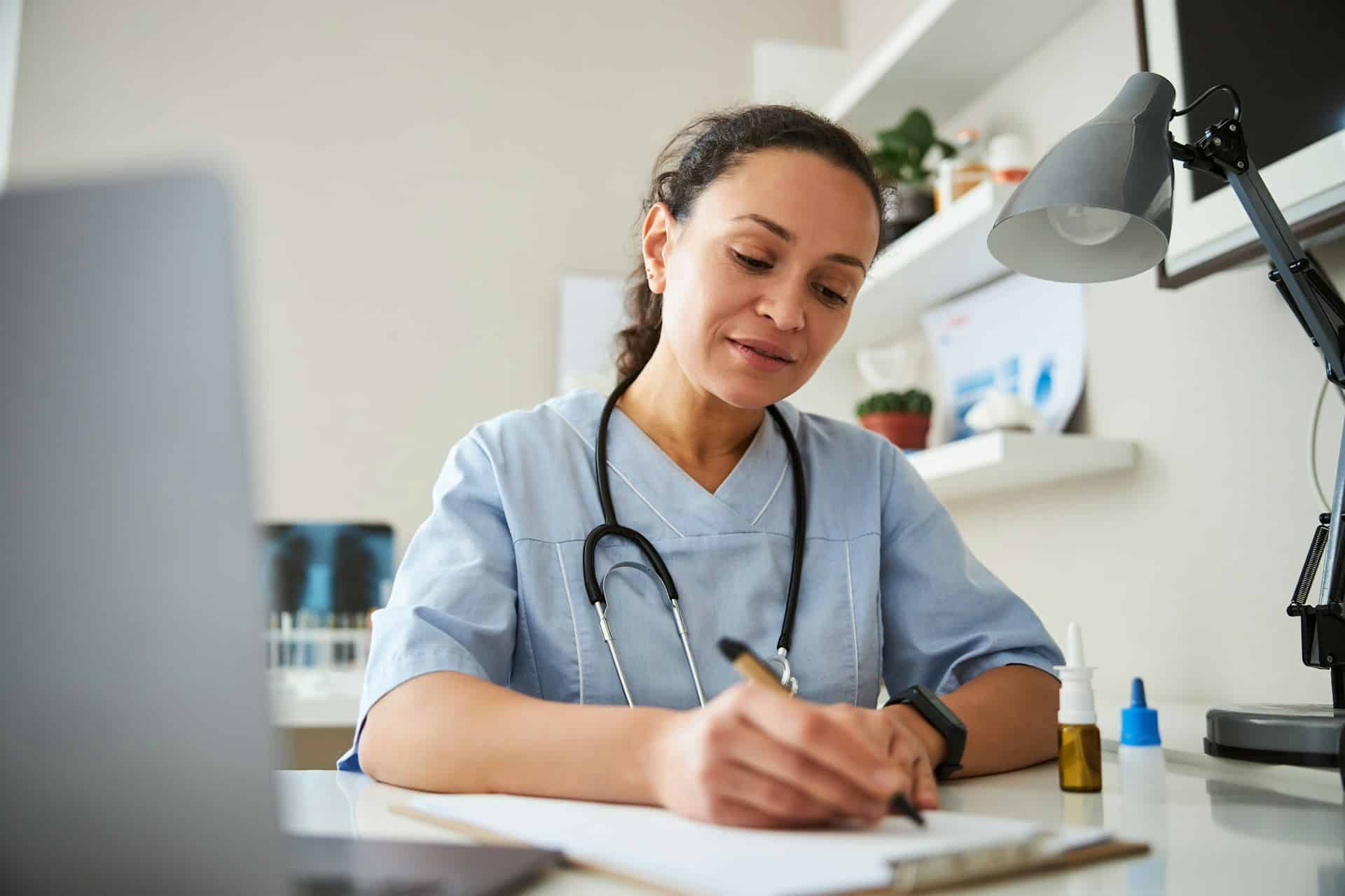 A young female doctor writing a note at her desk, representing Ontario employees being terminated after a medical leave