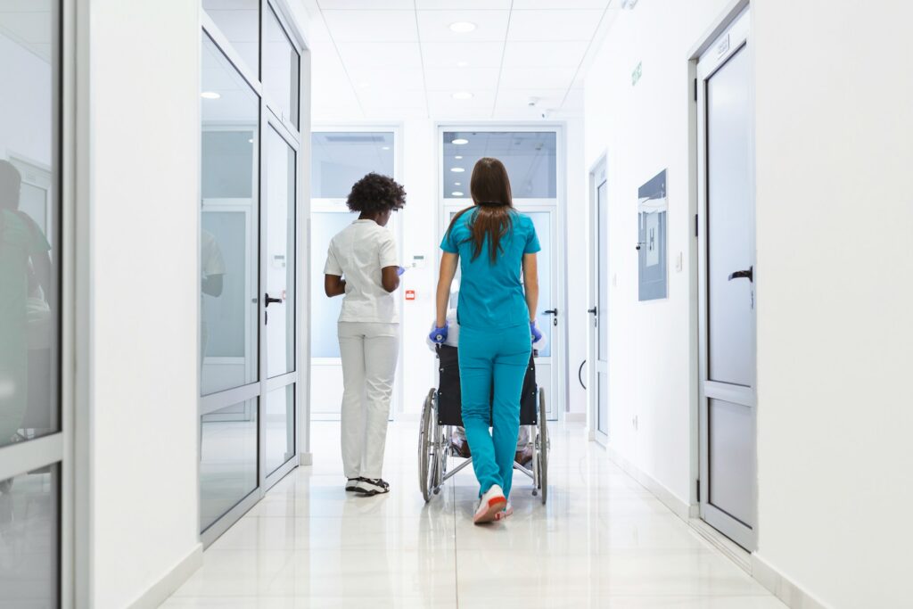 Two hospital workers push a wheel chair down a stark white hallyway, representing LTD benefits & wrongful resignation.