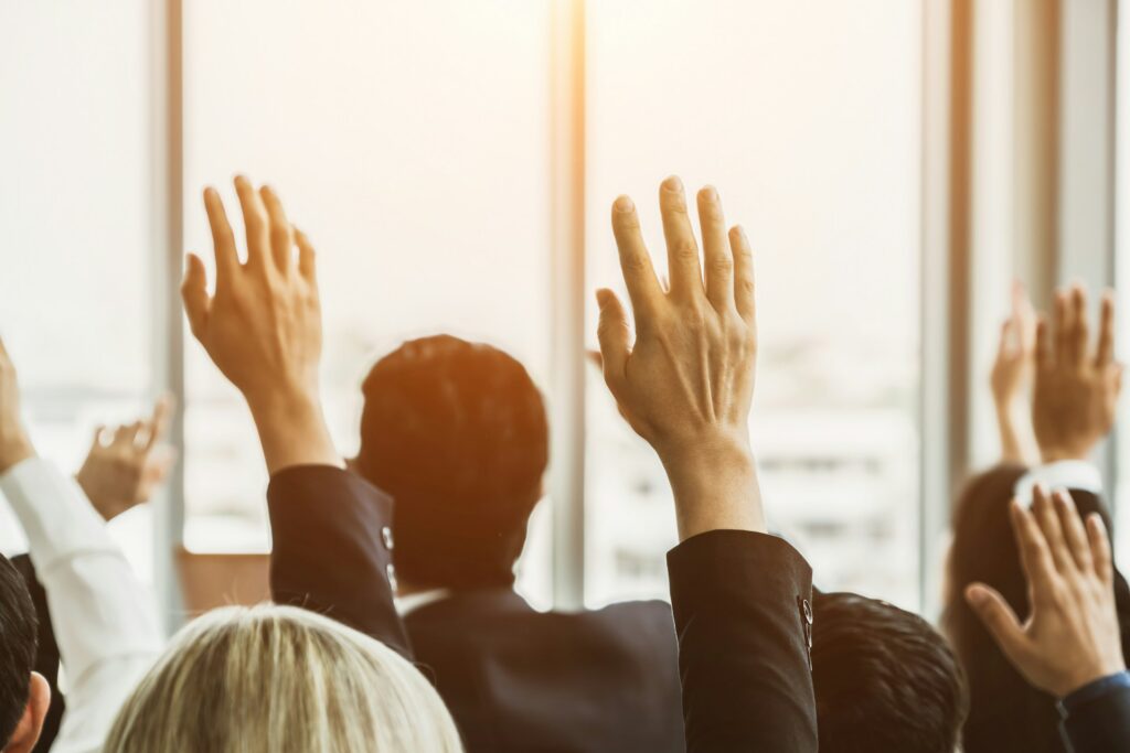 A group of employees raising their hands in a meeting, representing union organizing drives and union avoidance FAQs for Toronto employers.