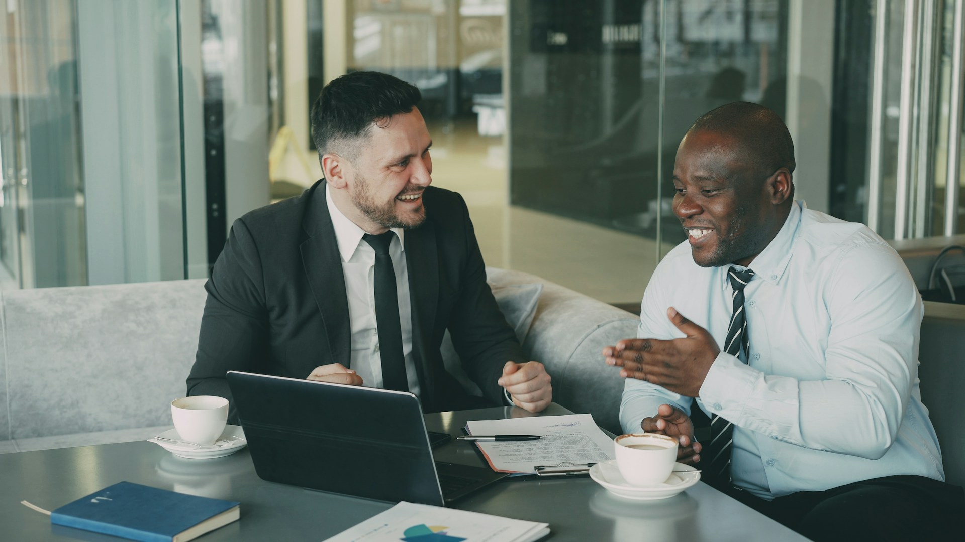 Two salespeople chatting and looking at a laptop together over coffee, representing sales team departures, use of confidential client information, and customer solicitation in Toronto.